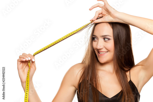 Happy attractive girl measured the length of her hair with a tape measure