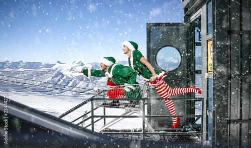 Christmas time and elf with gifts. Mountains landscape and snowflakes. 