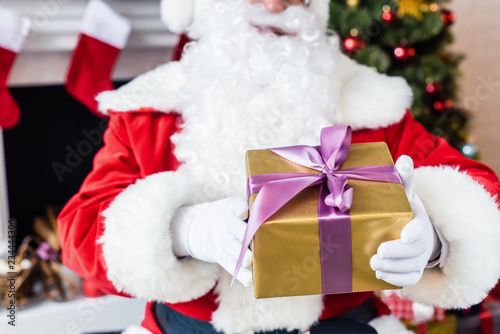 close-up partial view of santa holding christmas present