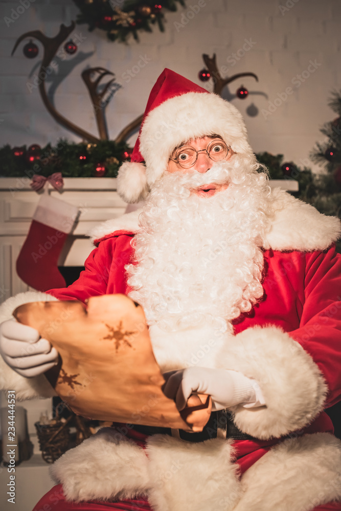 surprised santa holding parchment with wishlist and looking at camera surprised santa holding parchment with wishlist and looking at camera