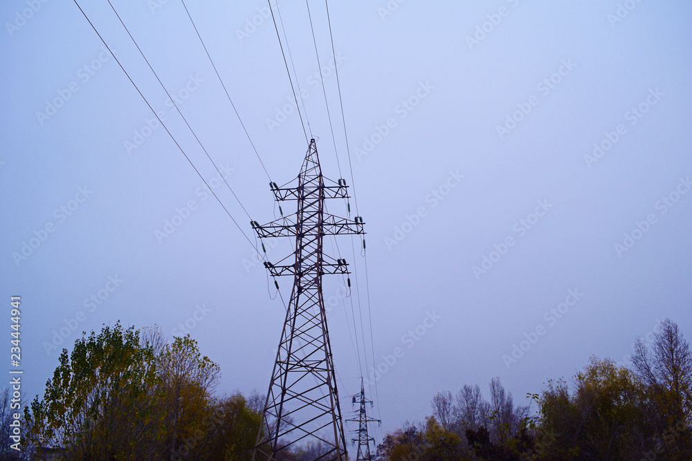 Bottom view of high-voltage poles against the sky in winter.