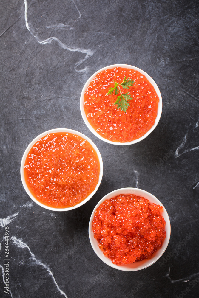 Red caviar Three species of salmon caviar in a white bowl on a black marble background. Variety of tastes.Seafood. Healthy Food Concept. Snack.Copy space for Text. Red caviar Three species of salmon caviar in a white bowl on a black marble background. Variety of tastes.Seafood. Healthy Food Concept. Snack.Copy space for Text.
