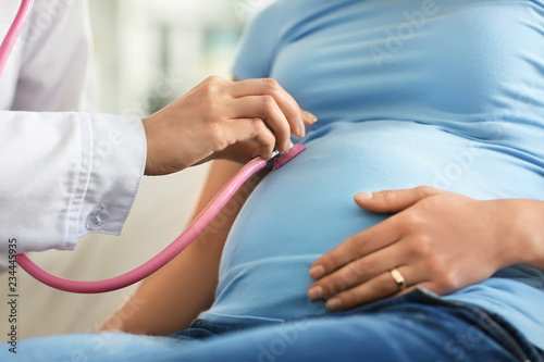 Young doctor examining pregnant woman in clinic photo