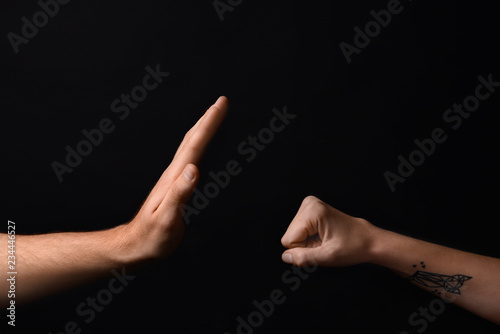 Man stopping aggressive woman on dark background