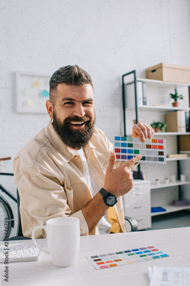 Handsome designer pointing at color palette in modern office Handsome designer pointing at color palette in modern office