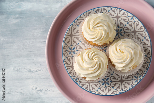 Plate with delicious cupcakes on grey table