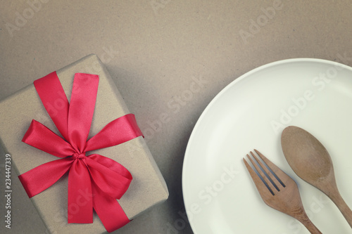 Wooden spoon on white plate and brown gift box.