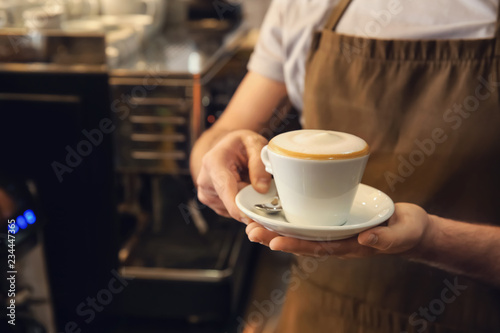 Barista with cup of fresh aromatic coffee in cafe