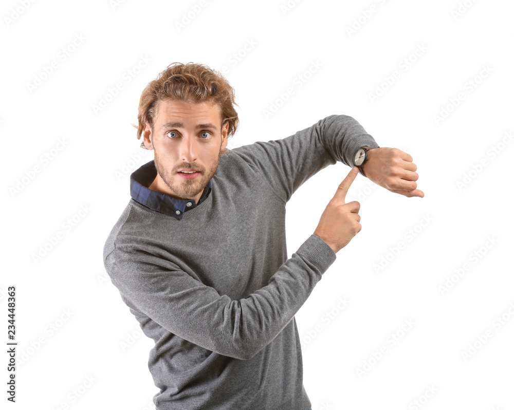 Young man pointing at his watch on white background Young man pointing at his watch on white background