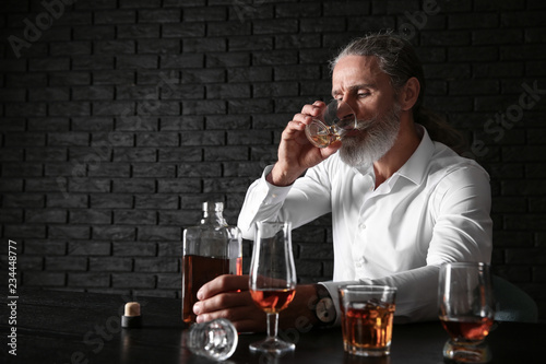 Depressed senior man drinki...