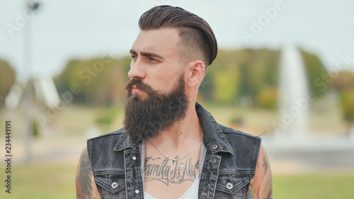 Fotografia Portrait of a brutal and bearded man with tattoos on his shoulders