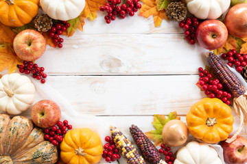 Top view of  Autumn maple leaves with Pumpkin and red berries on white wooden background. Thanksgiving day concept.