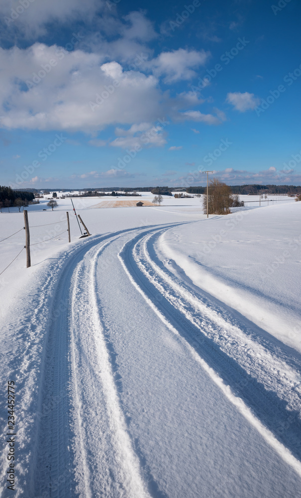 winterliche nicht geräumte Landstraße in der verschneiten Landschaft