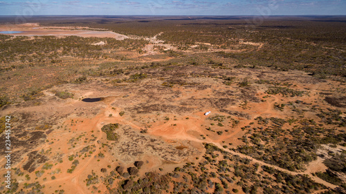 Oblique aerial view from drone of caravan and four wheel drive vehicle camped in the outback on the edge of the Nullarbor Plain in Australia.