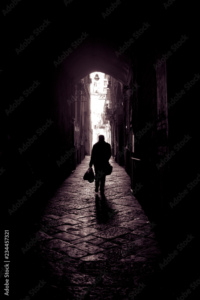 Silhouette of people walking In the lanes of the center of Naples, Italy