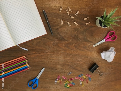 Office desk table with set of colorful supplies, with blank notes, crumpled paper and plant. Top view.