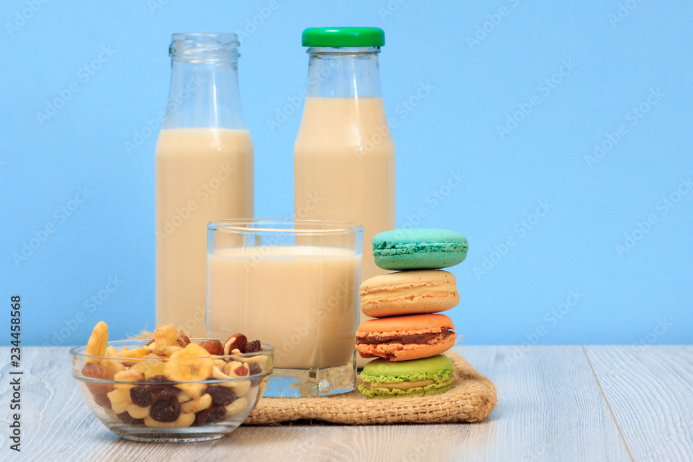 Bottles and glass of milk, bowl with muesli, macaroons on sackcloth. Bottles and glass of milk, bowl with muesli, macaroons on sackcloth.