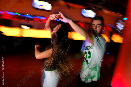 Pareja joven bailando salsa y bachata en una fiesta en club nocturno