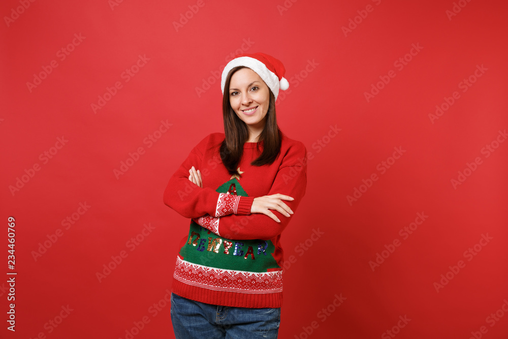 Pretty merry young Santa girl in knitted sweater, Christmas hat holding hands crossed isolated on bright red wall background. Happy New Year 2019 celebration holiday party concept. Mock up copy space. Pretty merry young Santa girl in knitted sweater, Christmas hat holding hands crossed isolated on bright red wall background. Happy New Year 2019 celebration holiday party concept. Mock up copy space.