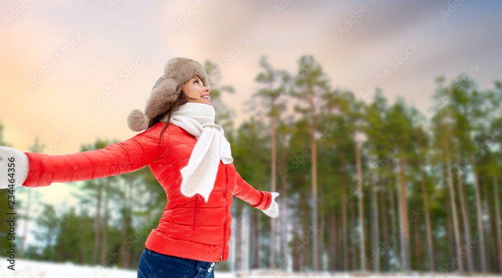 people, season and leisure concept - happy woman in fur hat outdoors over winter forest background