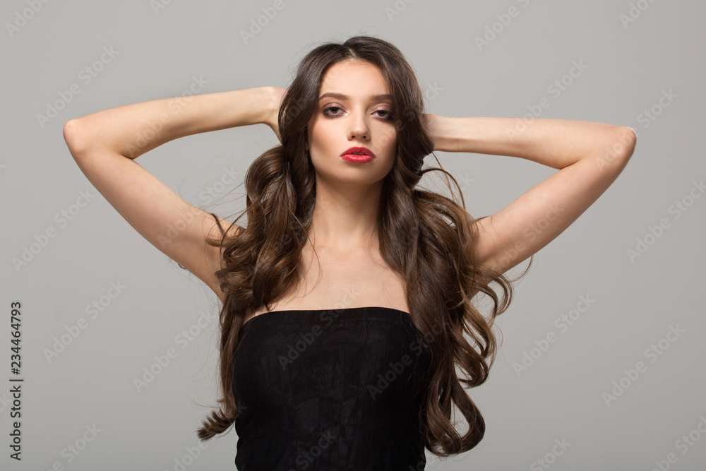 Fashion woman with curly shiny long hair. Gray background Fashion woman with curly shiny long hair. Gray background