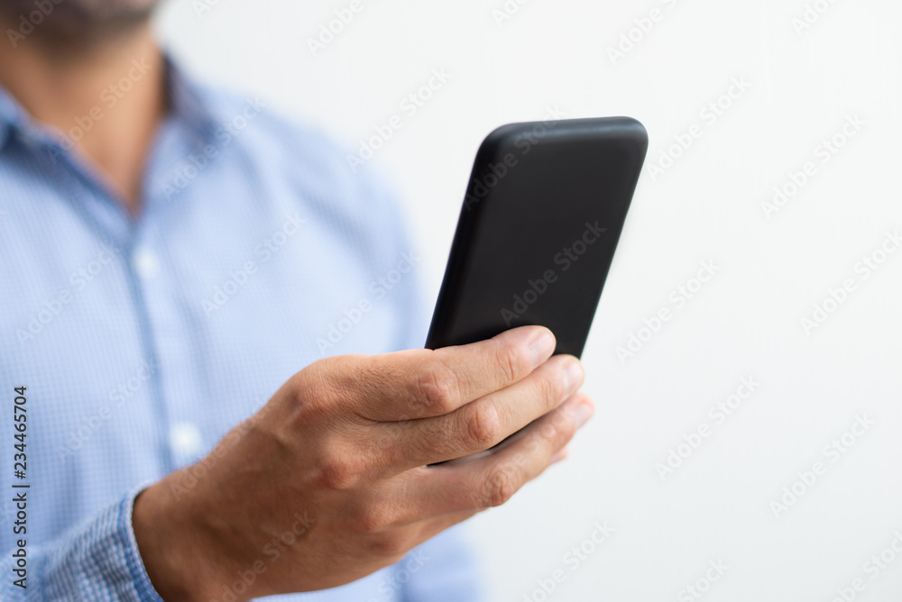 Closeup of man holding and browsing on smartphone. Person texting on digital gadget. Technology and communication concept. Cropped view. Closeup of man holding and browsing on smartphone. Person texting on digital gadget. Technology and communication concept. Cropped view.