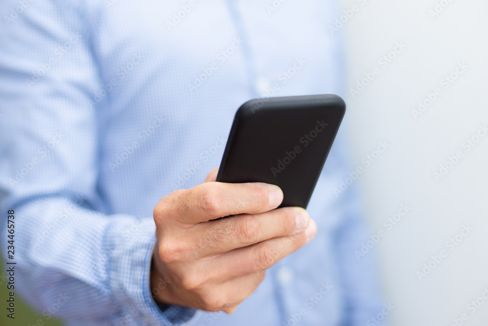 Closeup of man holding and using smartphone. Person texting on digital gadget. Technology and communication concept. Cropped front view. Closeup of man holding and using smartphone. Person texting on digital gadget. Technology and communication concept. Cropped front view.