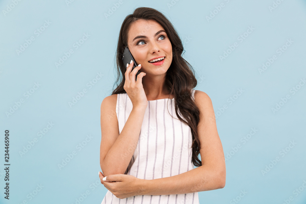 Woman posing isolated over blue background wall talking by mobile phone. Woman posing isolated over blue background wall talking by mobile phone.