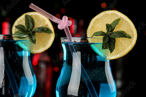 Cocktail blue lagoon in a cocktail glass with lemon and mint on a brown wooden table in the bar.