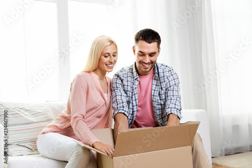delivery, mail and people concept - happy couple with open parcel box at home