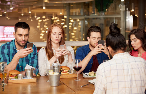 leisure  technology  lifestyle and people concept - friends with smartphones dining at restaurant