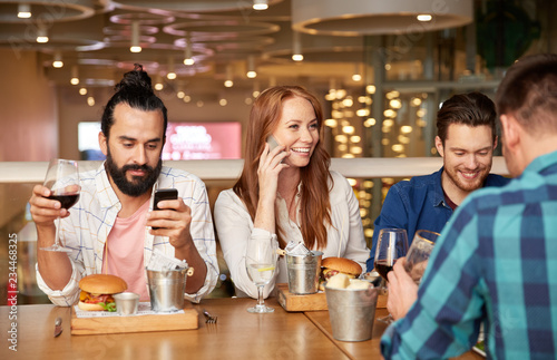 leisure and people and concept - friends having dinner and drinking red wine at restaurant