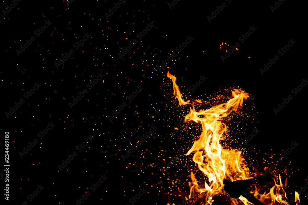 Burning woods with firesparks, flame and smoke. Strange weird odd elemental fiery figures on black background. Coal and ash. Abstract shapes at night. Bonfire outdoor on nature. Strenght of element.