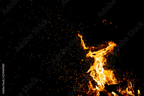 Burning woods with firesparks, flame and smoke. Strange weird odd elemental fiery figures on black background. Coal and ash. Abstract shapes at night. Bonfire outdoor on nature. Strenght of element.