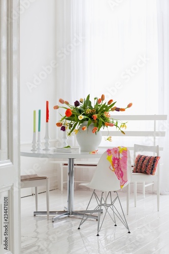 Luxuriant bouquet of multicoloured tulips on dining table in white interior photo