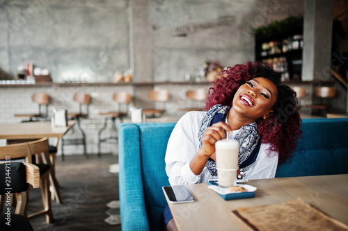 Attractive african american curly girl sitting at cafe with latte.