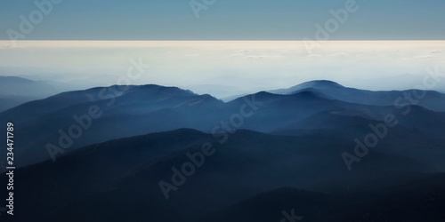 Peaceful blue nature background with foggy Bucegi mountains in Carpathians seen from Cota 2000, Sinaia resort, Romania © elephotos
