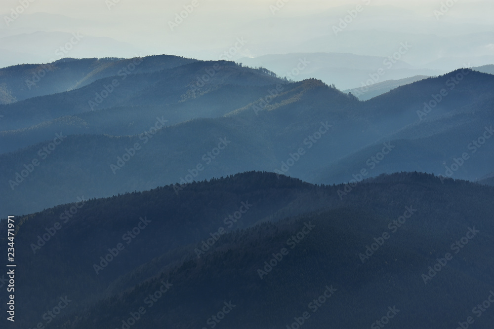Peaceful blue nature background with foggy Bucegi mountains in Carpathians seen from Cota 2000, Sinaia resort, Romania Peaceful blue nature background with foggy Bucegi mountains in Carpathians seen from Cota 2000, Sinaia resort, Romania