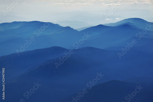 Peaceful blue nature background with foggy Bucegi mountains in Carpathians seen from Cota 2000, Sinaia resort, Romania © elephotos