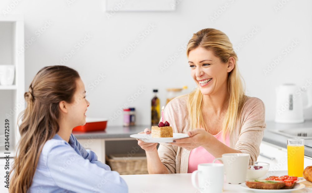 family, celebration and people concept - happy mother giving daughter piece of birthday cake at home kitchen family, celebration and people concept - happy mother giving daughter piece of birthday cake at home kitchen