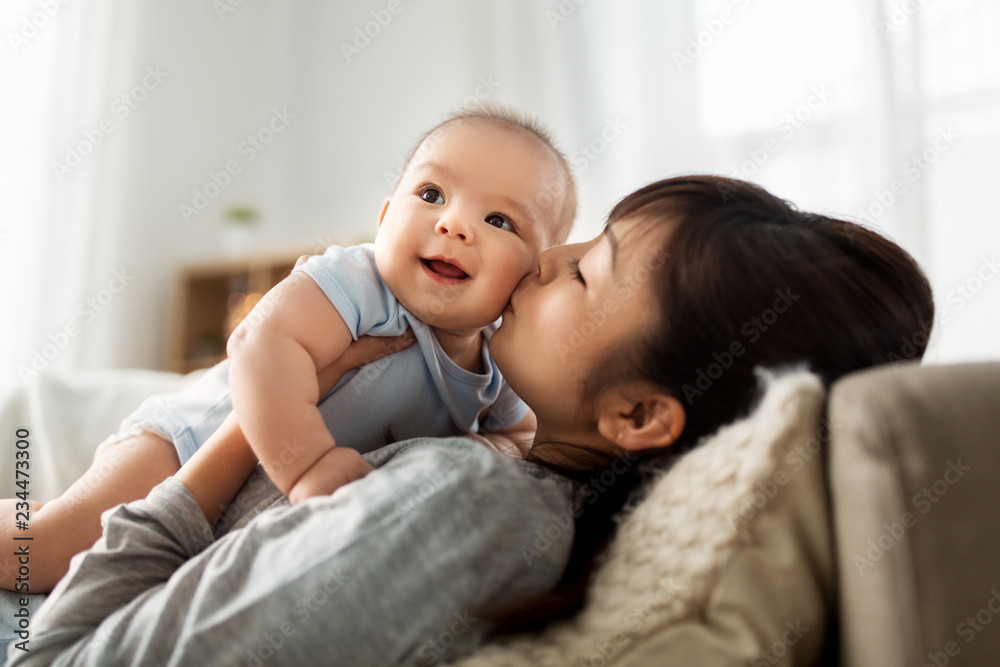 family and motherhood concept - happy young asian mother kissing little baby son at home family and motherhood concept - happy young asian mother kissing little baby son at home