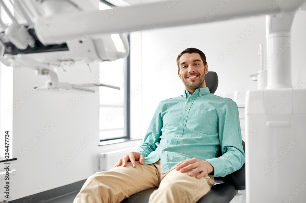 medicine, dentistry and healthcare concept - happy smiling male patient on chair at dental clinic