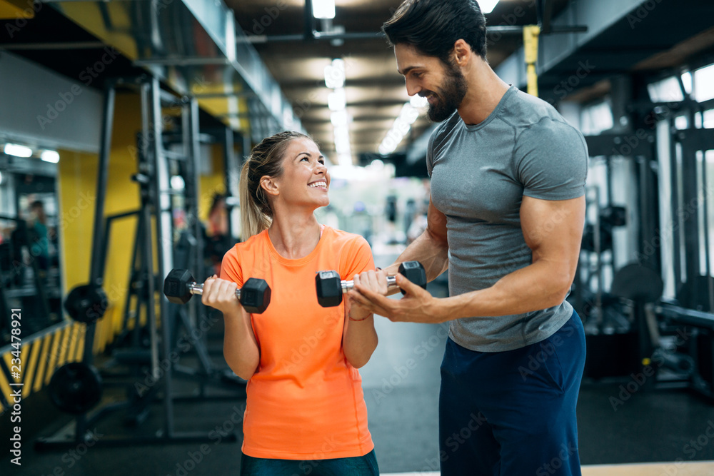 Obraz premium Personal trainer assisting beautiful woman lose weight