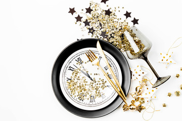 New Year table setting. Black tableware and gold confetti decoration. Flat lay, top view.