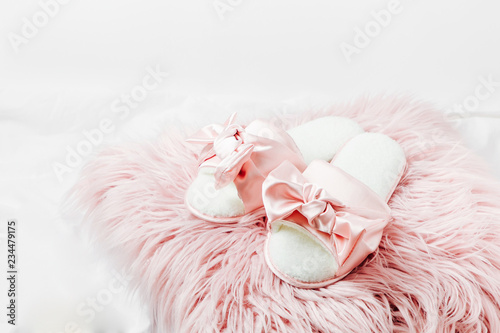 Beautiful female slippers and a cup of coffee on a pink fur cushion on the bed