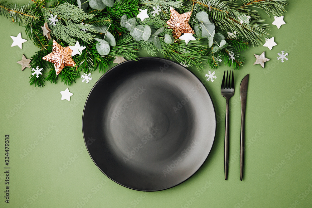 Christmas table setting. Black tableware and decoration with fir-tree branch. Flat lay, top view. Christmas table setting. Black tableware and decoration with fir-tree branch. Flat lay, top view.