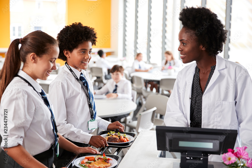 High School Students Wearing Uniform Paying For Meal In Cafeteria High School Students Wearing Uniform Paying For Meal In Cafeteria