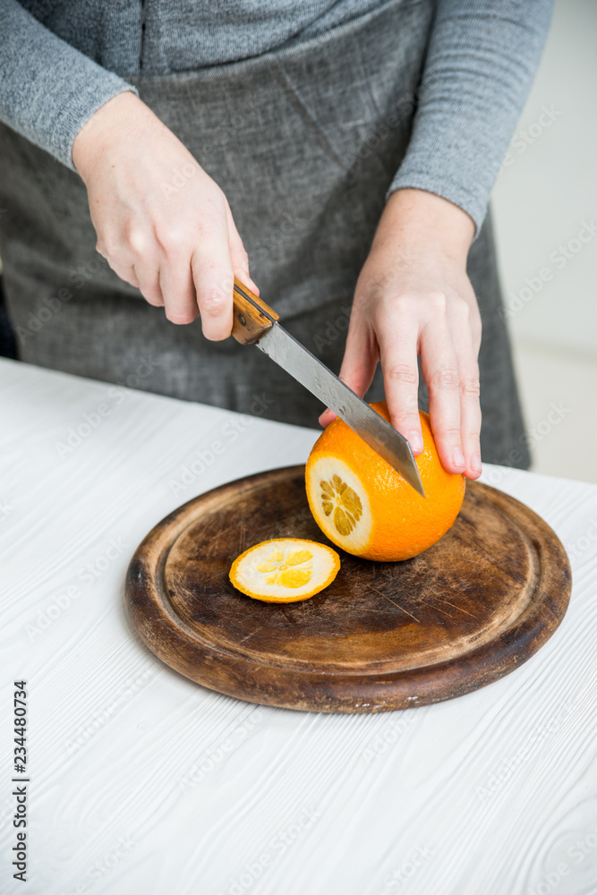 Woman cuts orange on board close view Woman cuts orange on board close view