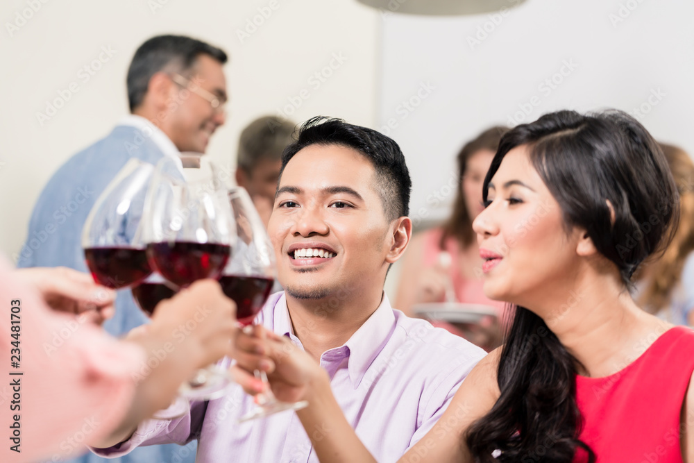 Smiling young couple toasting wineglasses with friends Smiling young couple toasting wineglasses with friends