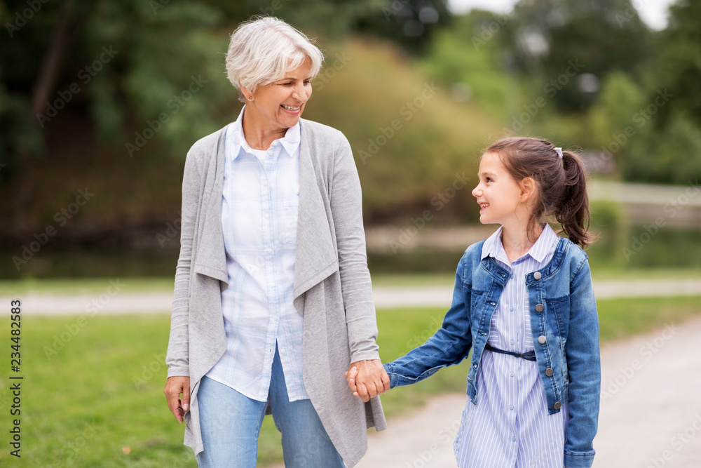 family, leisure and people concept - happy grandmother and granddaughter walking at summer park family, leisure and people concept - happy grandmother and granddaughter walking at summer park